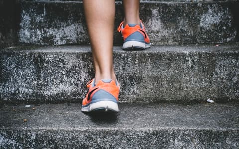 A runner in trainers climbing a flight of concrete steps, loading the Achilles tendon