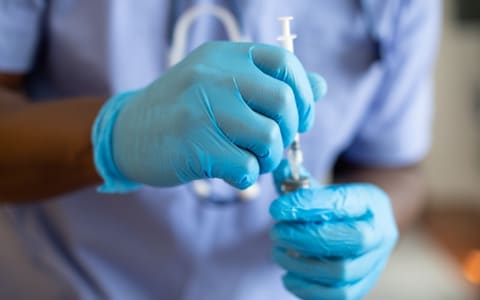 Gloved hands drawing platelet-rich plasma into a syringe before injection